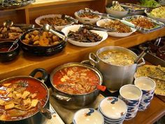 a buffet filled with lots of different types of food on top of a wooden table