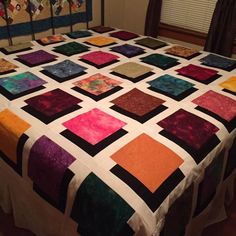 a bed with a colorful quilt on top of it