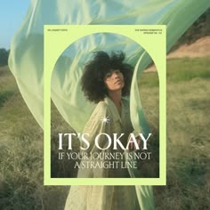 a woman with curly hair standing in a field holding a green scarf over her head