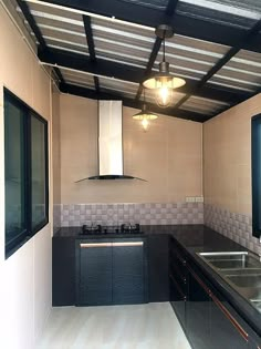 an empty kitchen with black counter tops and stainless steel appliances on the wall, under a metal roof