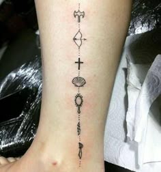 a woman's foot with tattoos on it and an anchor, cross, shell