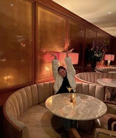 a woman sitting at a table with her arms in the air