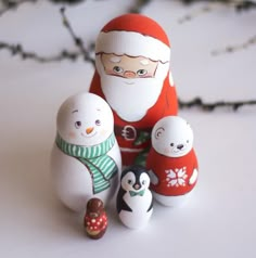 a group of snowmen with santa clause on their face and one penguin in the foreground