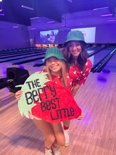 two girls holding up signs in bowling alleys with the words the best little on them