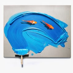 two goldfish swimming in blue water on a gray and silver painting with popsicle