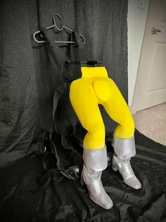 a person in yellow and white boots is sitting on a black sheet with a backpack behind them