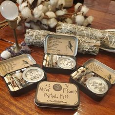 four tins filled with different items on top of a wooden table next to cotton floss