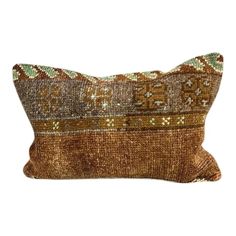 a brown and green decorative pillow on a white background with an embroidered design in the middle