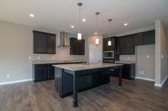 an empty kitchen with wooden floors and black cabinets