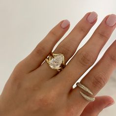 a woman's hand with two rings on it and an engagement ring in the middle