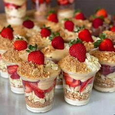 desserts with strawberries and other toppings are arranged on a white table top