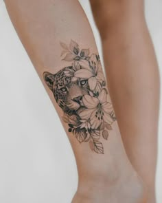 a woman's leg with a tattoo of a tiger and flowers on it