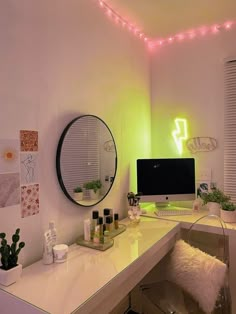 a white desk topped with a computer monitor next to a mirror and potted plants