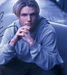 a young man sitting on top of a couch next to a wall with autographs