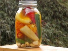 a jar filled with lots of different types of fruit and veggies on top of a wooden table