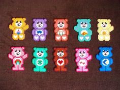 six different colored teddy bears are arranged in the shape of small pixeles on a brown surface