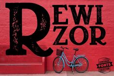 a blue bicycle parked in front of a red wall with the letter r on it