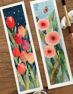 two watercolor cards with flowers on them next to some paintbrushes and an egg