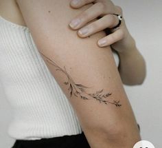 a woman's arm with a tattoo on it that has an arrow and leaves