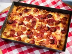 a square pizza sitting on top of a red and white checkered table cloth