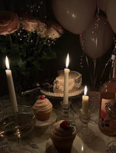 a table topped with cupcakes and candles next to bottles of wine on top of a table