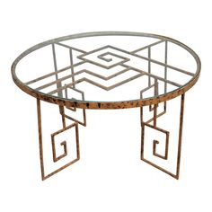 a round glass table with metal frame and geometric design on the top, against a white background