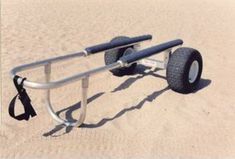 a beach cart sitting in the sand with two large wheels on it's side