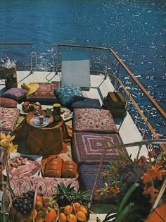 an outdoor seating area on the deck of a boat with lots of pillows and fruit