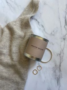 a can of coffee sitting on top of a white marble counter next to a pair of scissors