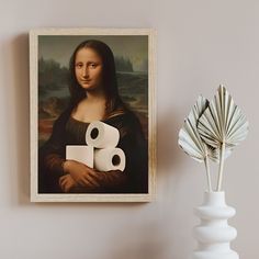 there is a painting on the wall next to a vase with two rolls of toilet paper