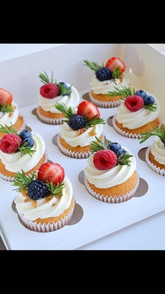 cupcakes with white frosting and raspberries on top are arranged in a pink tray