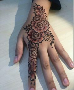 a woman's hand with a henna tattoo on her left hand and an intricate flower