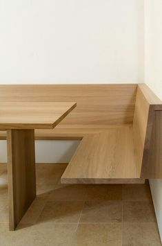 a wooden bench sitting on top of a tiled floor next to a white wall in a room