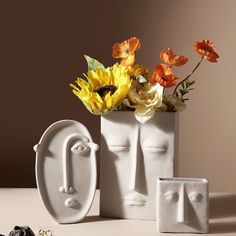 there is a vase with flowers in it and two faces on the front, one has an eye