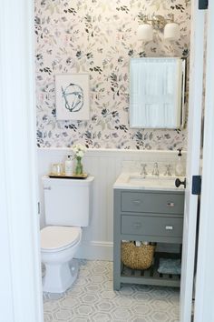 a white toilet sitting next to a sink in a bathroom under a mirror above a vanity