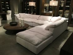 a large white sectional couch sitting on top of a floor next to a wooden table