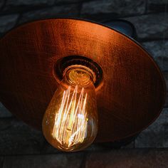 a light bulb that is on the side of a building with brick walls in the background