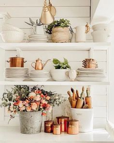 a kitchen shelf filled with dishes and flowers on top of eachother's shelves