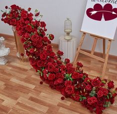 red roses are arranged in the shape of a heart on a wooden floor next to an easel