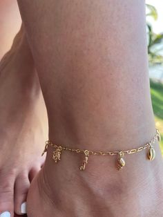 COLOR: GOLD PLATED MATERIAL: STAINLESS STEEL The "Under The Sea" gold-plated jewelry anklet from Dainty By Gio! This gorgeous piece is inspired by the beauty of the ocean and beach, and features a charming little beach charm that will transport you to the sandy shores with each wear. Crafted with love, including a durable base metal plated with a layer of lustrous gold, this anklet is not only stunning but also affordable. Enjoy the luxury and style of real gold without the hefty price tag! At D Ankle Charm Bracelet, Under The Sea Jewelry, Beachy Gold Jewelry With Starfish Charm, Dainty Gold Jewelry For Vacation, Gold Starfish Charm Jewelry For Beach, Gold Beach Jewelry With Starfish Charm, Gold Jewelry With Starfish Charm For Beach, Gold Ocean-inspired Jewelry With Dangling Charms, Ocean-inspired Gold Jewelry With Dangling Charms