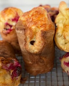 several pastries sitting on a cooling rack with cranberry toppings in them