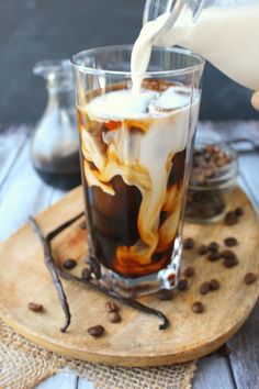 someone pouring milk into a glass filled with coffee