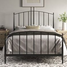 a black metal bed frame with white sheets and pillows on top of it in a bedroom