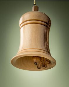 a wooden bell ornament hanging from a ceiling fixture with a green wall in the background