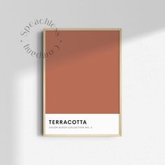 the terracotta color is shown in a wooden frame on a white wall with a shadow