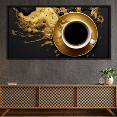 a cup of coffee sitting on top of a wooden table next to a wall mounted painting