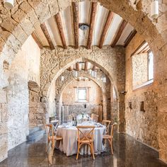 a dining table is set up in an old stone walled room with arched doorways