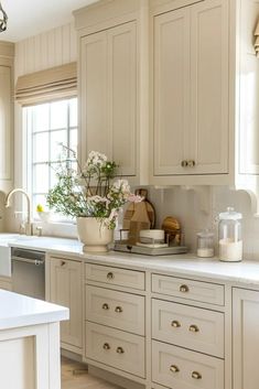 a kitchen filled with lots of white cupboards and counter top next to a window