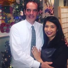 a man standing next to a woman in front of a christmas tree