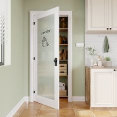 a kitchen with green walls and white cupboards, an open door to the pantry